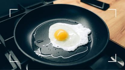 Black non-stick pan on heat cooking an egg