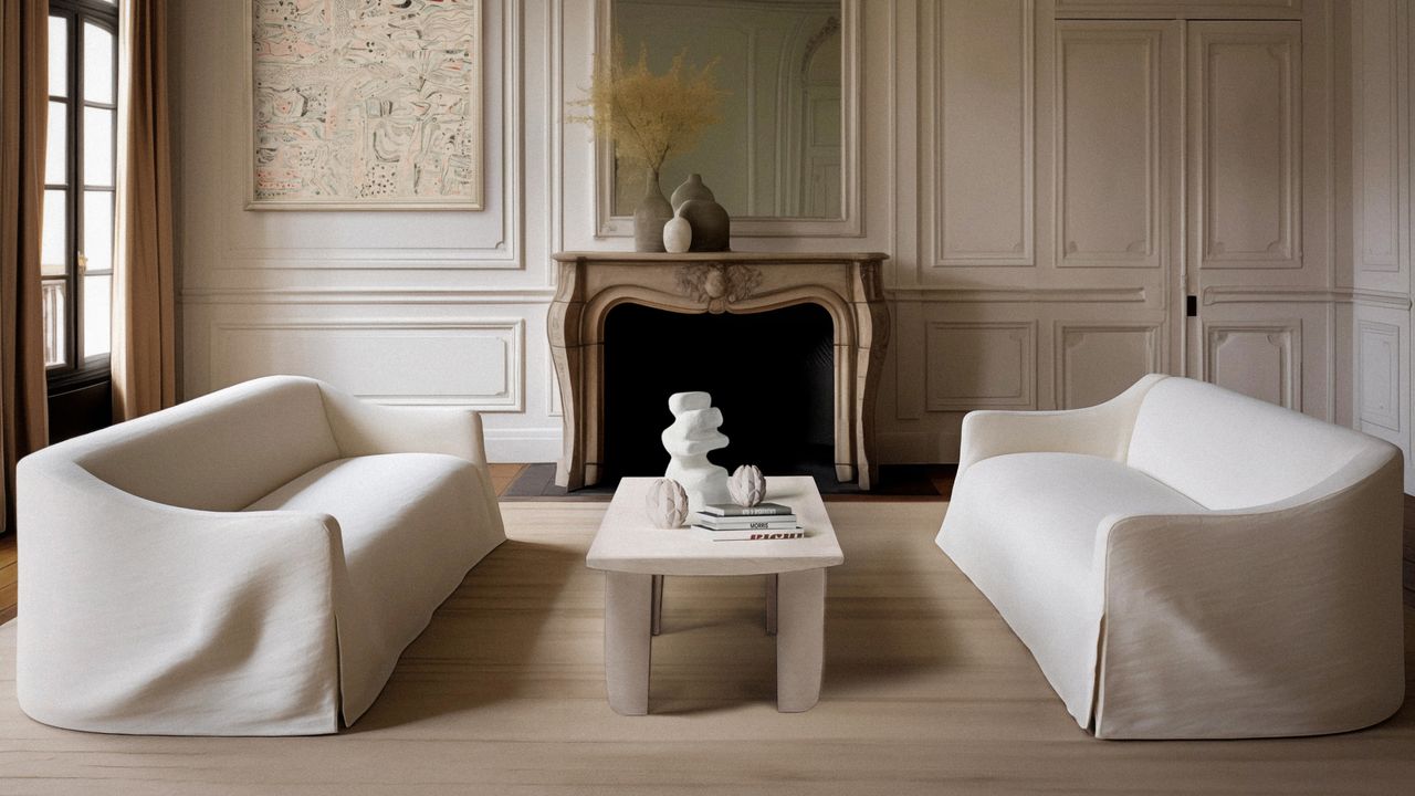 Living room with facing white sofas, white coffee table and white paneled walls, fireplace with mirror above and wood floor