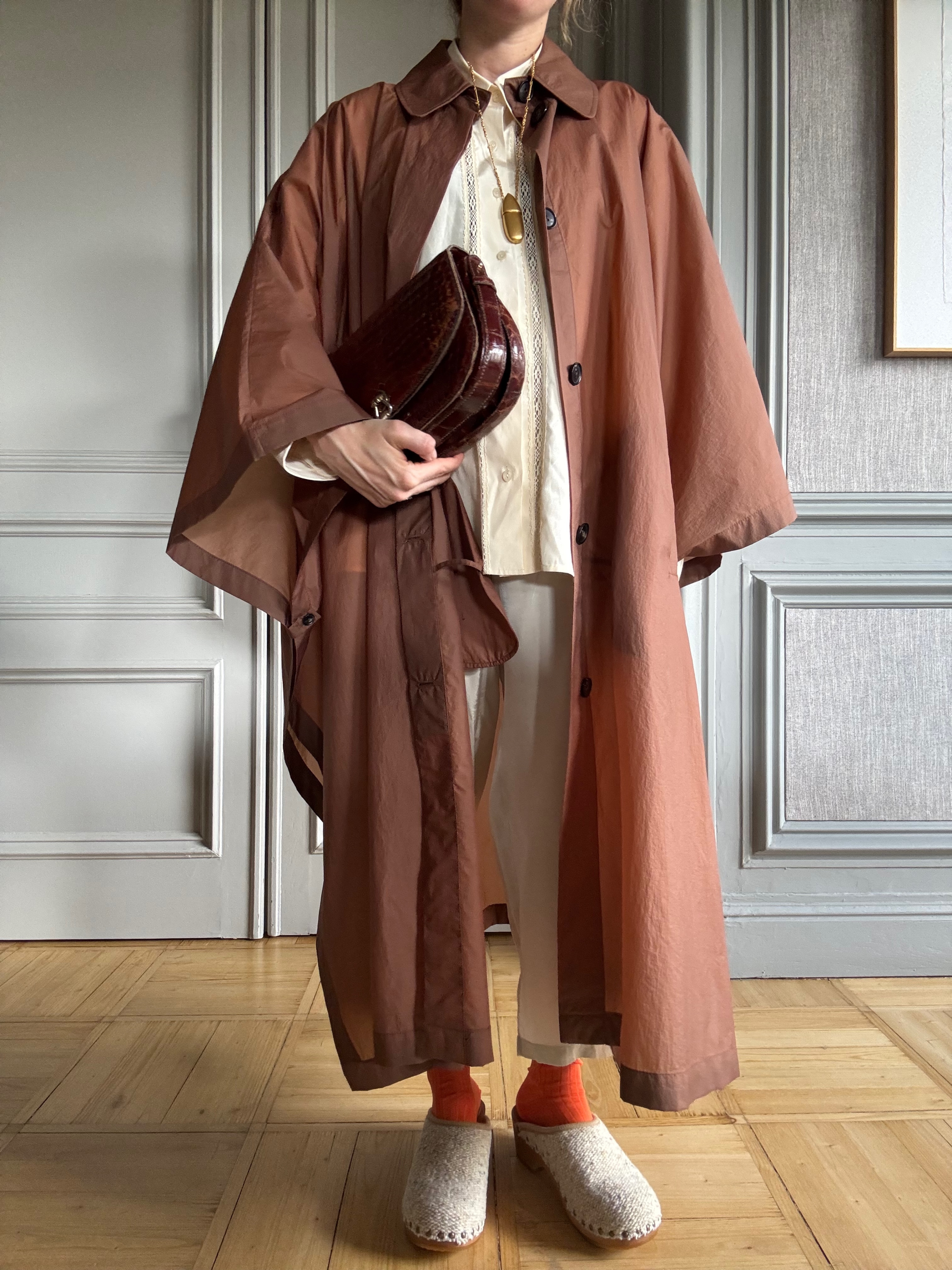Blanca Miro wears a brown chiffon trench coat, cream trousers and clogs