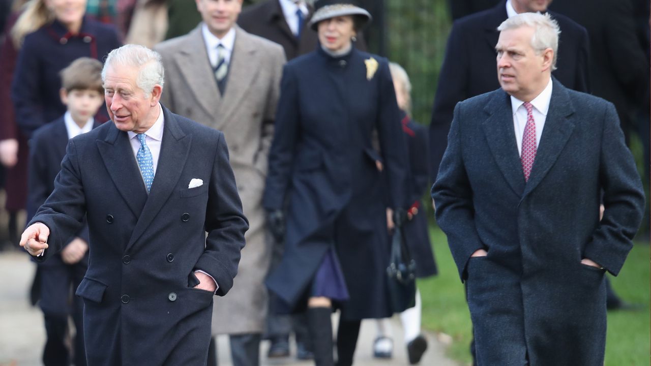 King Charles wearing a long coat walking next to Prince Andrew walking with his hand in his pockets