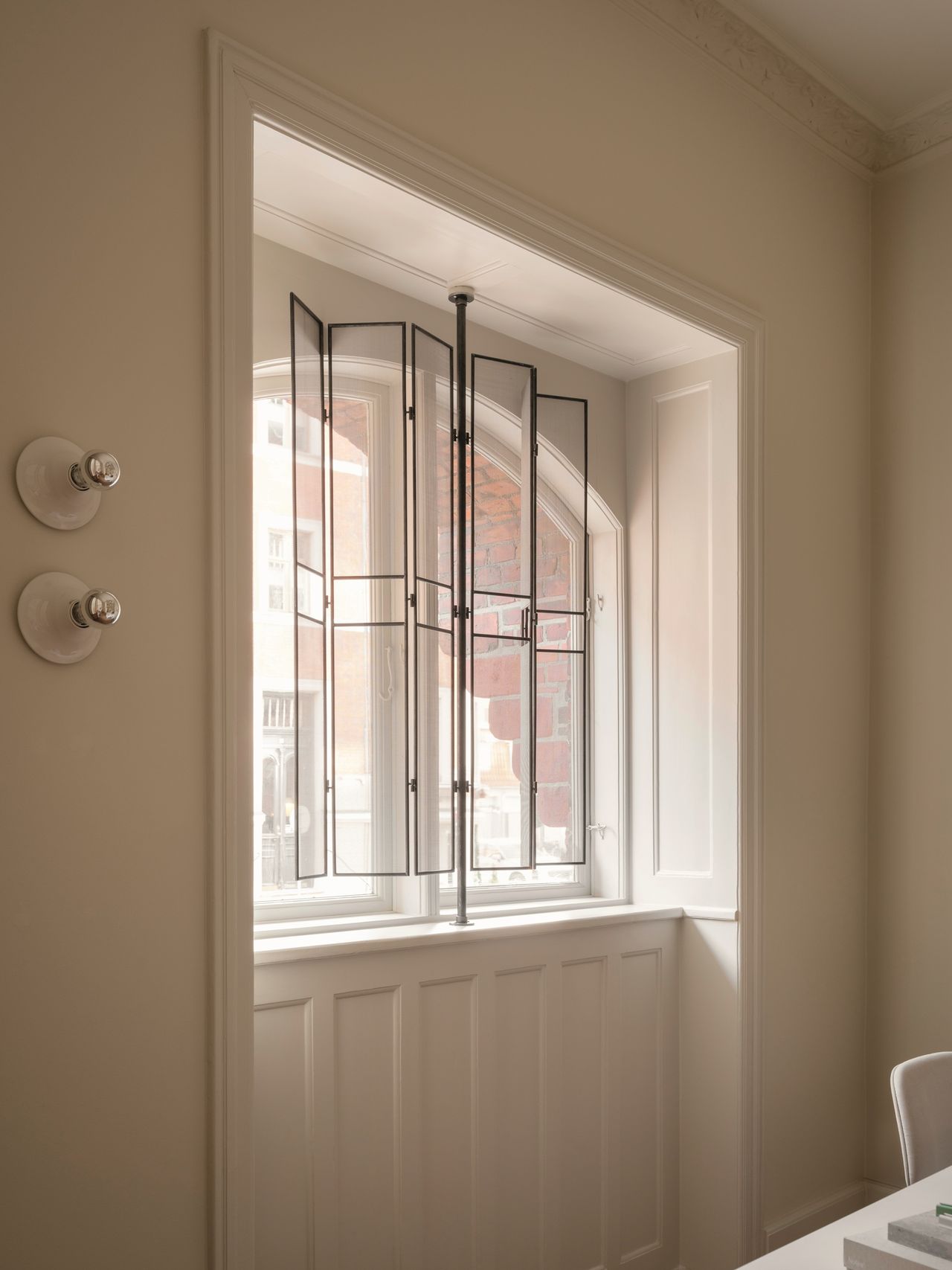 glass shutters extended across windows with white walls and wall sconces