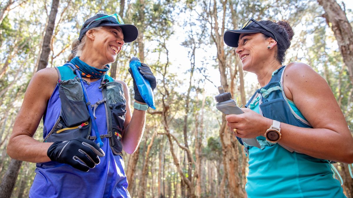 Two trail runners pausing for water break in woodland