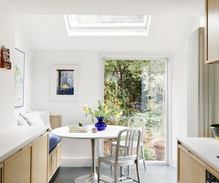 small kitchen diner with white walls, yellow units and skylight above built in diner area at end