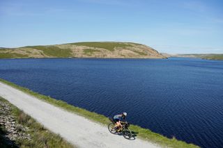 Anna Abram cycling by the Claerwen reservoir on a gravel ride along the Trans Cambrian Way
