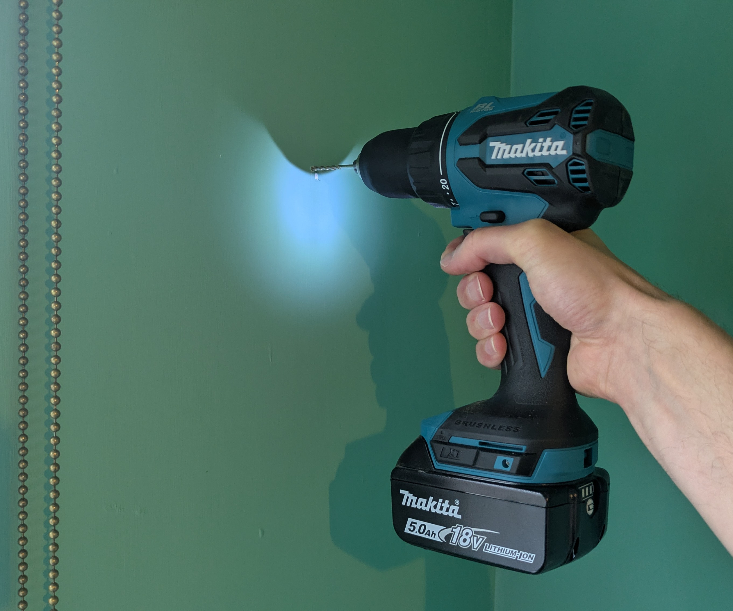 A combi drill making a hole in a painted wall