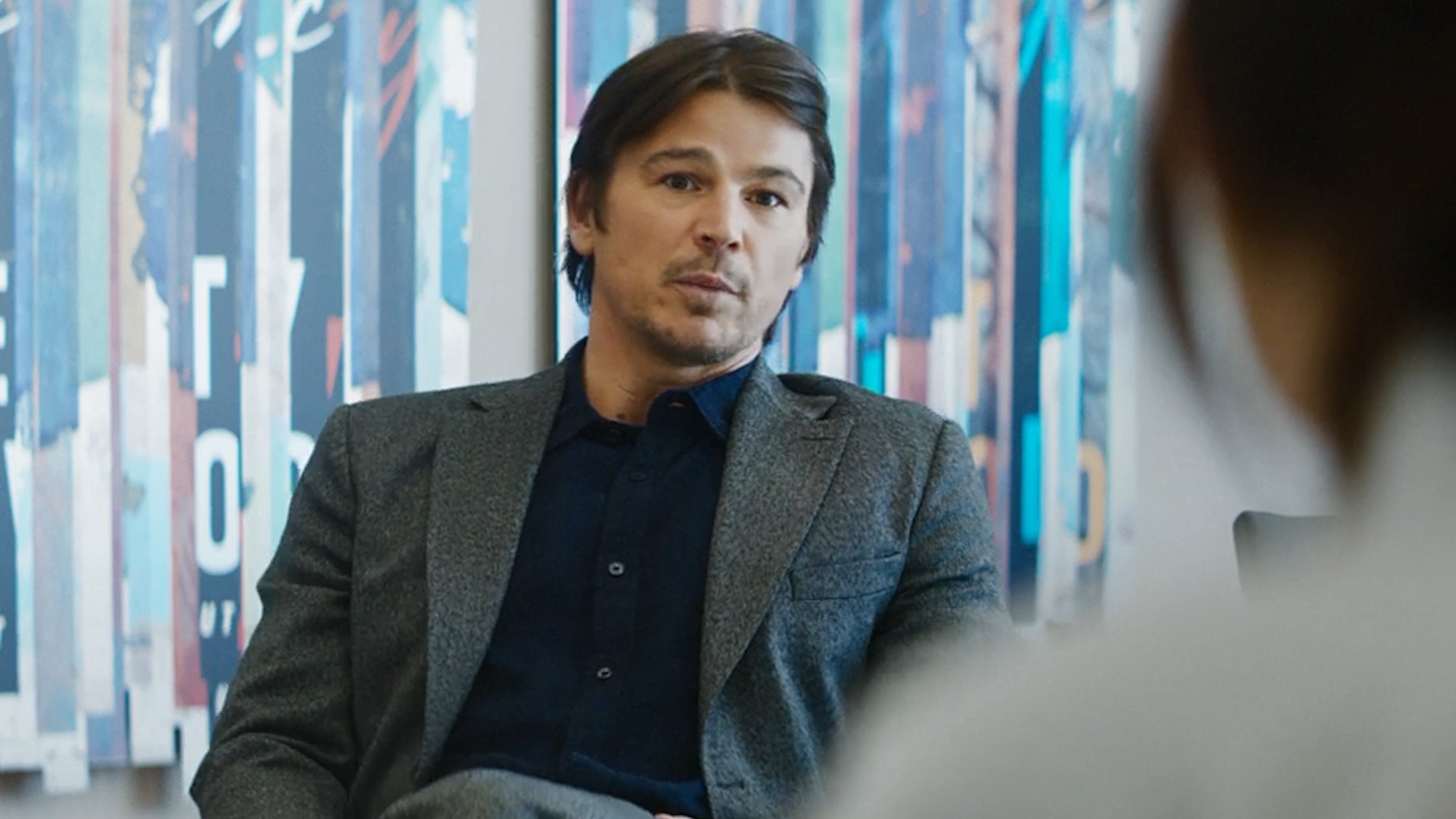 Josh Hartnett sitting in a conference room in Verity