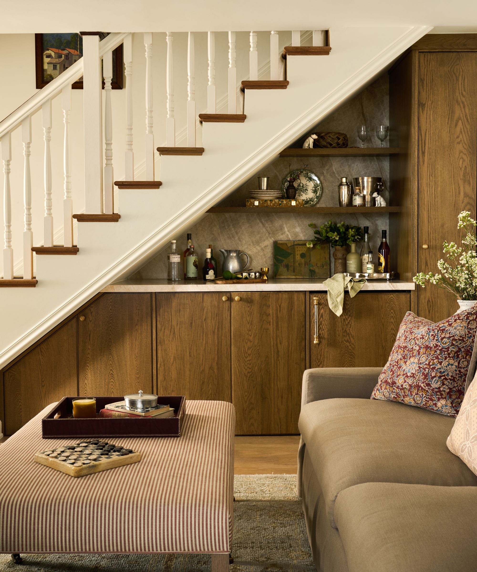 a white and wooden staircase with a warm wood home bar tucked beneath