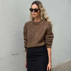 Anouk wears a brown sweater and black pencil skirt.