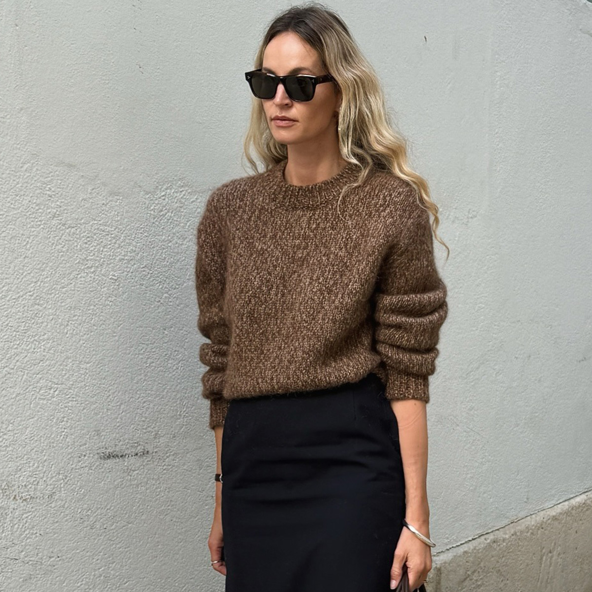 Anouk wears a brown sweater and black pencil skirt.