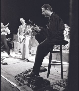 Robert Fripp (with Adrian Belew in the background) performing at Discipline Club, London, 10 May 1982.