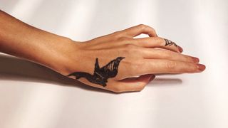 woman's hand and arm with bird tattoo on the hand