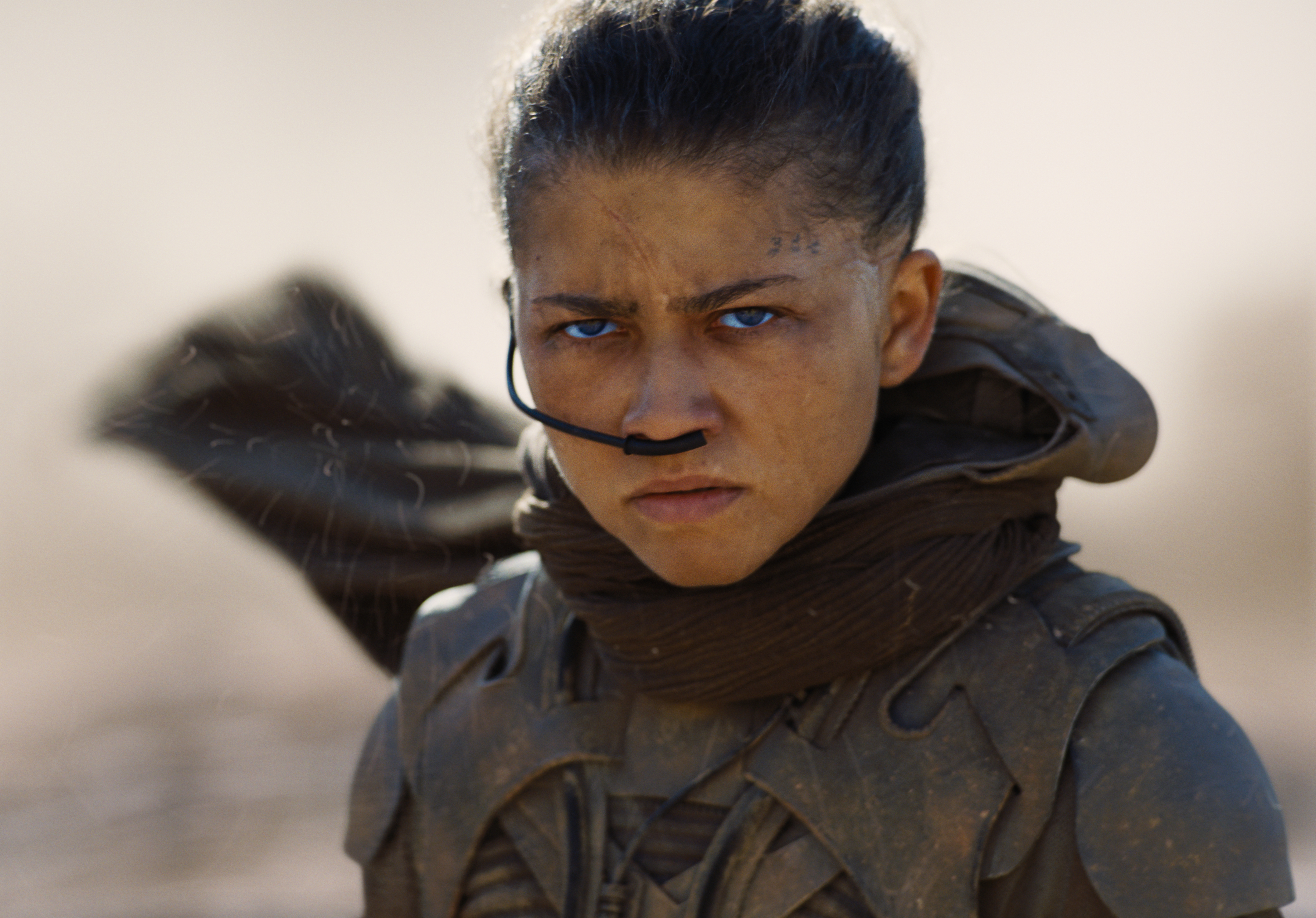 zendaya as chani with her blue eyes and wearing armor in a windy desert in a still from dune part three
