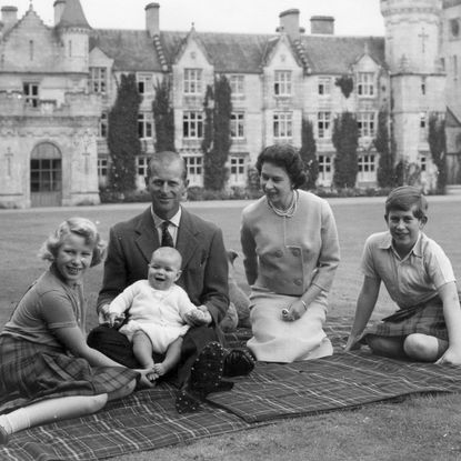 Queen Elizabeth sitting on a picnic blanket with Prince Philip and their kids at Balmoral Castle
