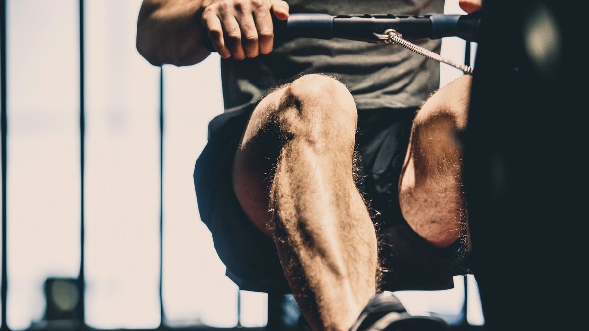 Unrecognisable man using rowing machine