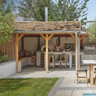 outdoor kitchen area with shelter, bench seating, and white breakfast bar