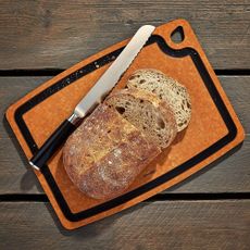 bread knife and sliced bread on wooden chopping board on wooden surface