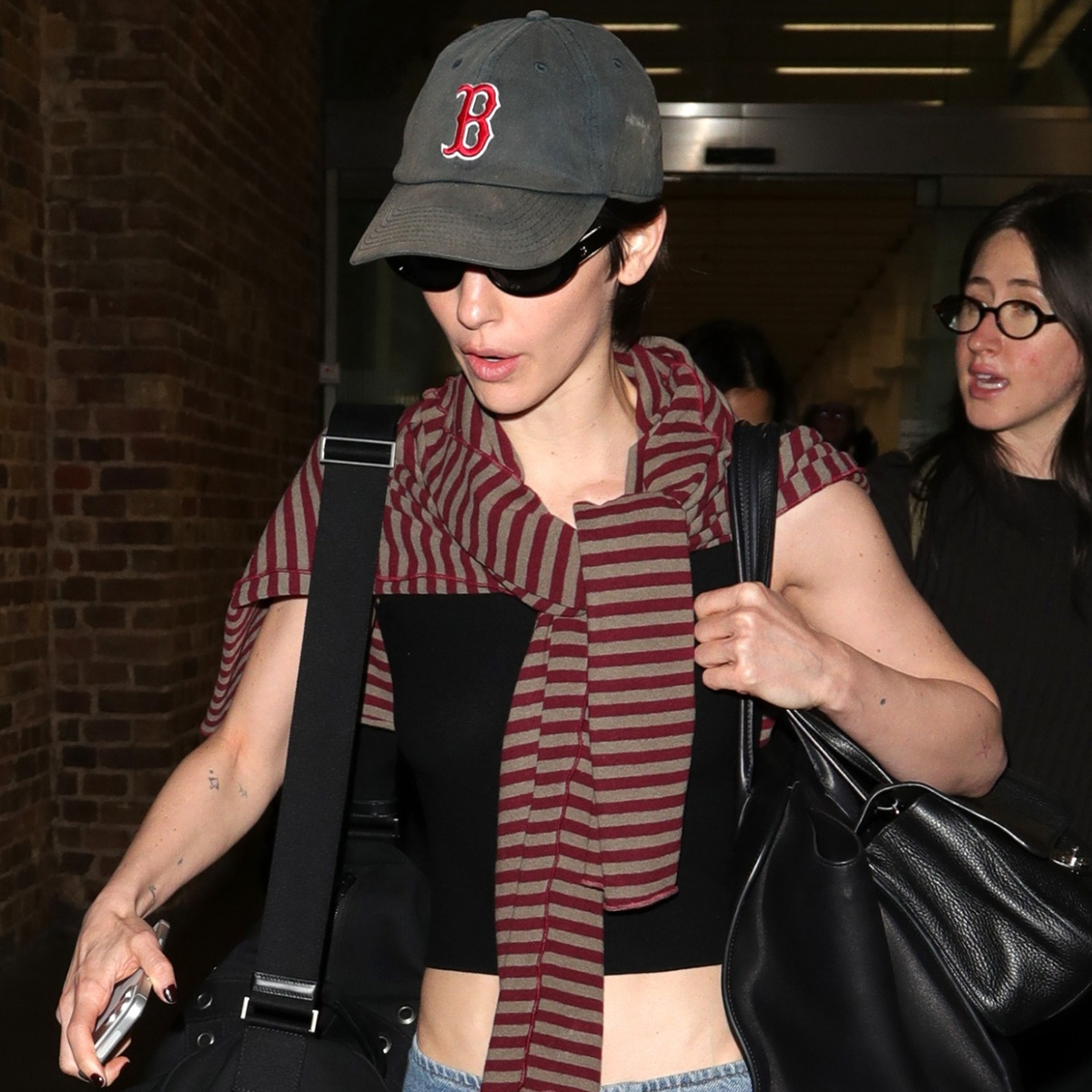gracie wears a boston hat, stripe sweater, and a black tank with low-rise jeans.
