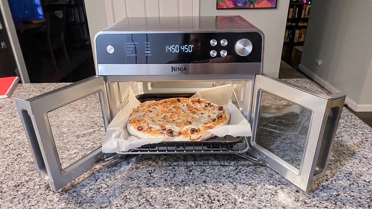 Ninja French Door Premier Air Fryer on a kitchen counter with doors open showing a cooked pizza
