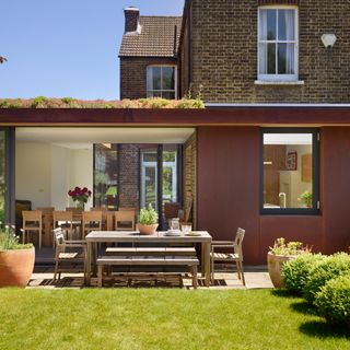 red wall house with garden and outdoor dinning table and chair