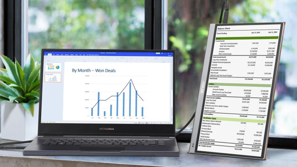 The Asus ZenScreen OLED MQ13AH, one of the best portable monitors, on a desk beside a laptop