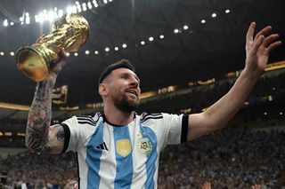 Lionel Messi of Argentina celebrates with the FIFA World Cup Qatar 2022 Winner's Trophy on Sergio 'Kun' Aguero's shoulders after the team's victory during the FIFA World Cup Qatar 2022 Final match between Argentina and France at Lusail Stadium on December 18, 2022 in Lusail City, Qatar.