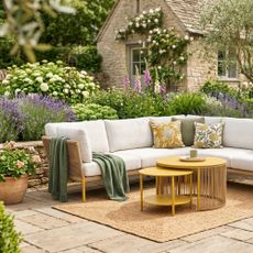 Yellow Ipanema outdoor nesting coffee table from Habitat with a corner outdoor sofa in an English garden