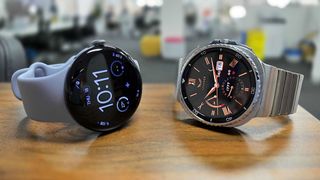 Google Pixel Watch 4 and Samsung Galaxy Watch 8 Classic placed side by side on bench top