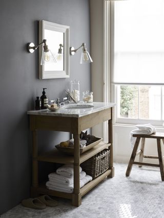 bathroom with stylish wood and marble bathroom sink vanity decorated with accessories and handy storage jars