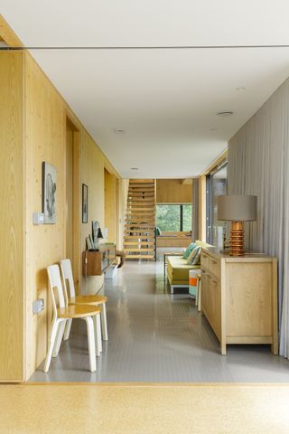 wood clad hallway with grey rubber floor and view of stairs