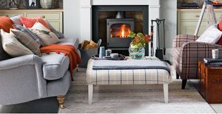 Grey living room with sofa and armchair facing each other in front of a log burner creating a social living space