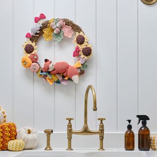 crochet autumn/fall wreath with fox and flowers hanging above a sink in the kitchen