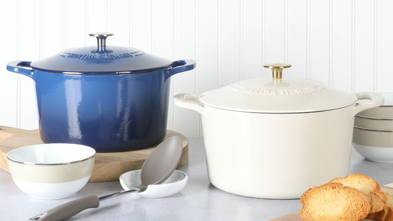 Two of the Martha Stewart Enameled Cast Iron Dutch Ovens in blue and white on a kitchen counter