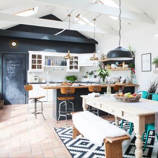 kitchen with black slate wall and white ceiling with rug on floor and dining area