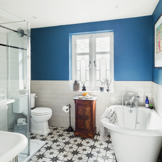 bathroom with blue and white wall bathtub and white windows