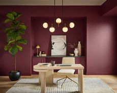 A home office space with a wooden desk a burgundy walls 