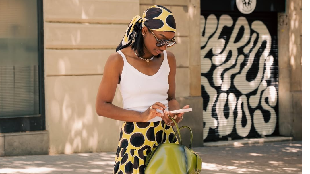 NYC woman wears a yellow and brown polka dot skirt with matching bandana and a white tank top.