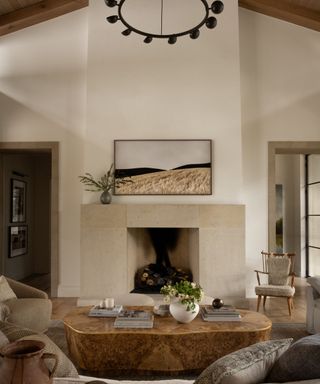 Cream walls living room with fireplace, candelabra, large stone coffee table and wooden and boucle chair