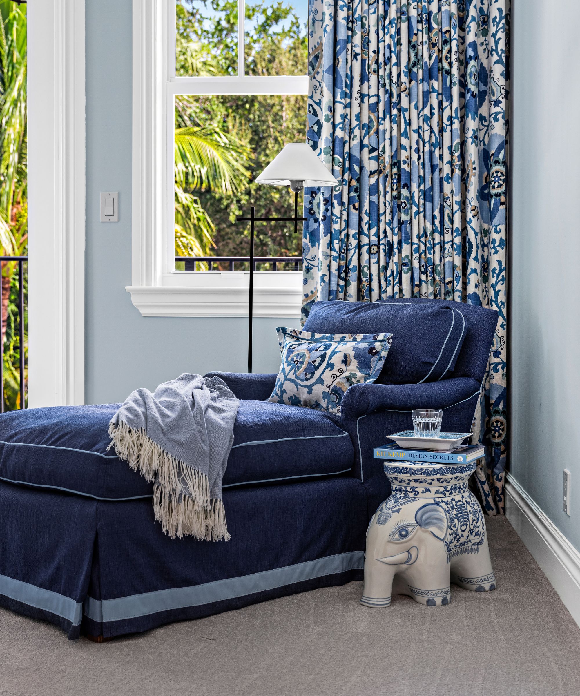 An antique chaise longue reupholstered in a dark blue fabric with white piping