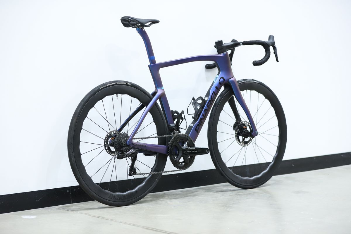 A blue pinarello dogma f stands against a white wall