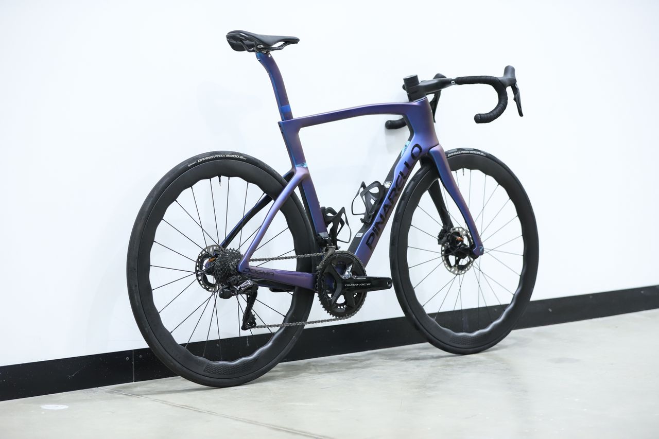 A blue pinarello dogma f stands against a white wall