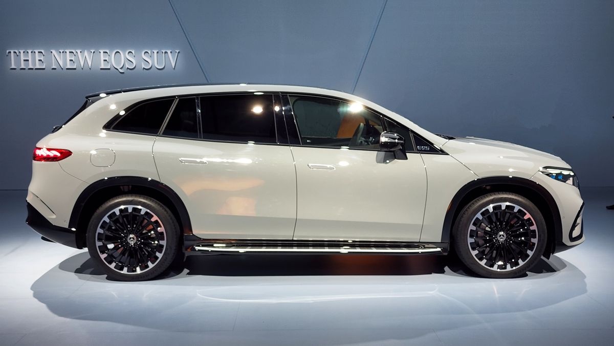 Side view of a white EQS SUV parked in a studio