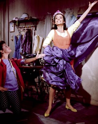 rita moreno singing with natalie wood as she dances with purple fabric in west side story