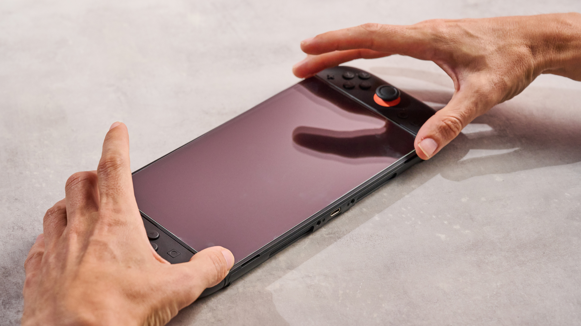 A man installing the Snakebyte Starter Kit S2 screen protector onto the Nintendo Switch 2.