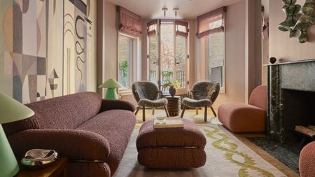 pink living room with mural on the wall, two twin armchairs in the window and green marble fireplace