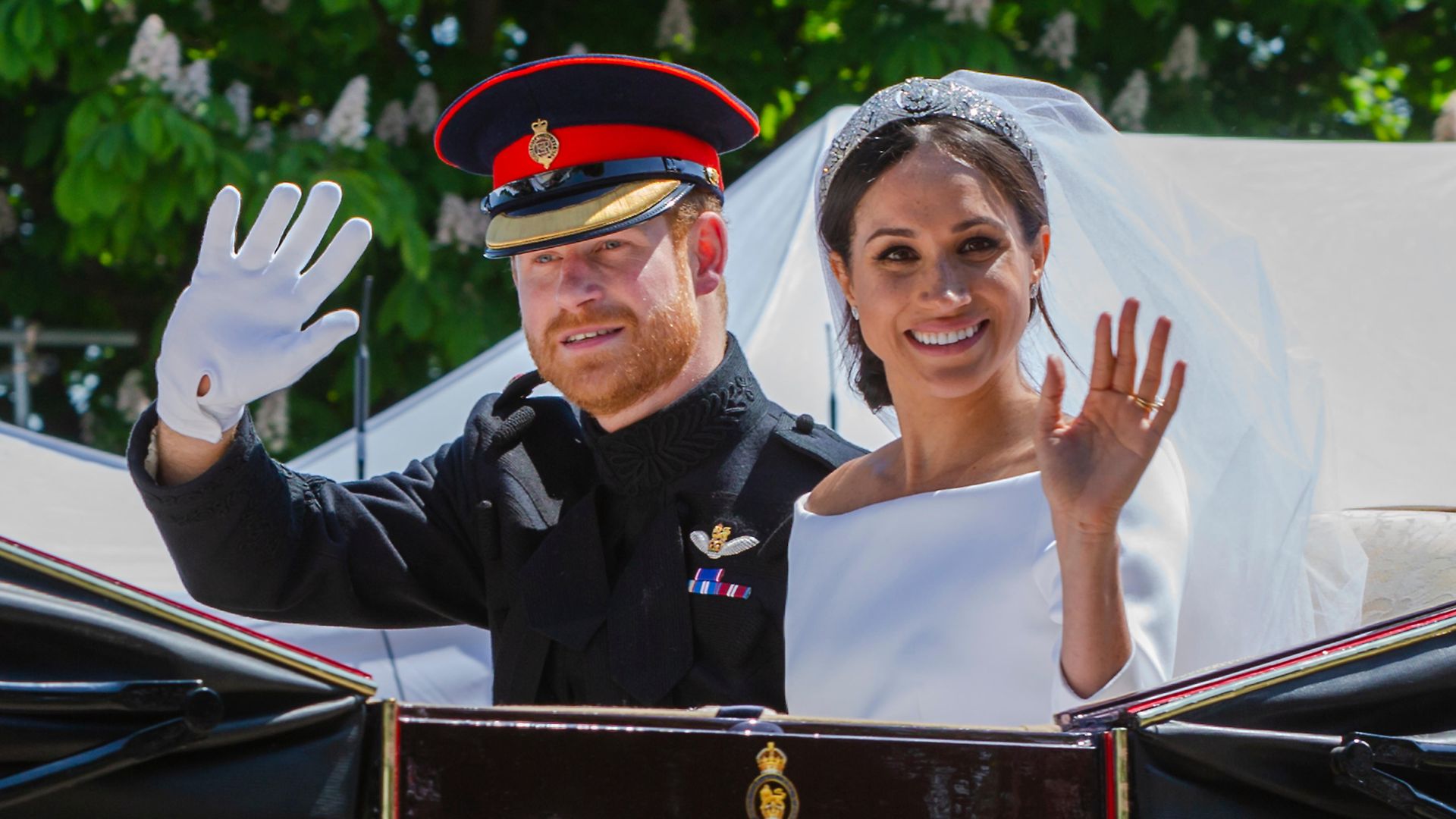 Meghan Sussex and Prince Harry waving from a carriage on their wedding day