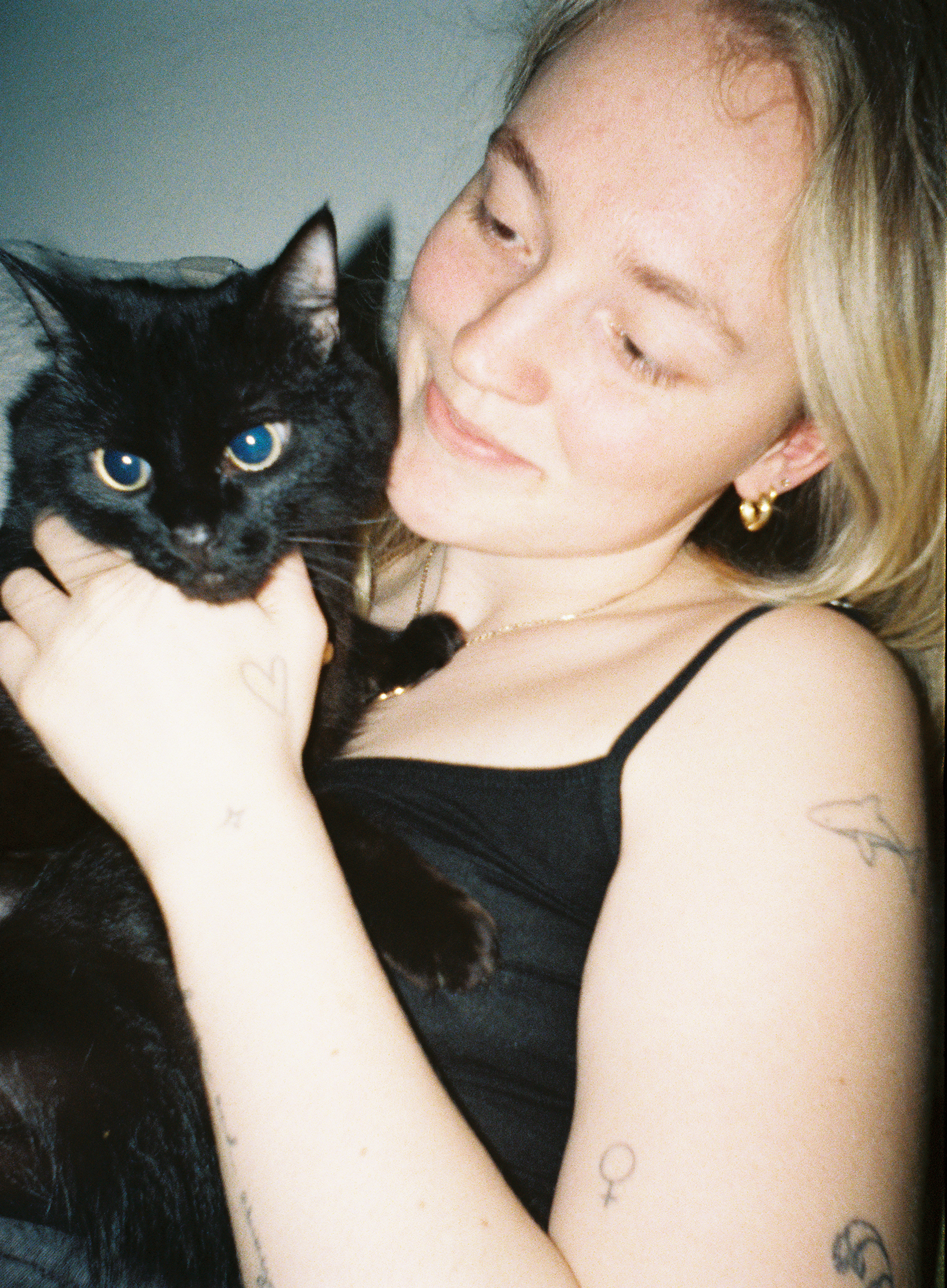 Sample image from Lomography Half-frame Simple Use Reloadable Film Camera showing a woman holding a black cat, lit with flash