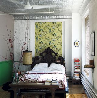 bed in bedroom with fan and books