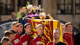 The coffin of Queen Elizabeth II with the Imperial State Crown resting on top is carried by the Bearer Party as it departs Westminster Abbey