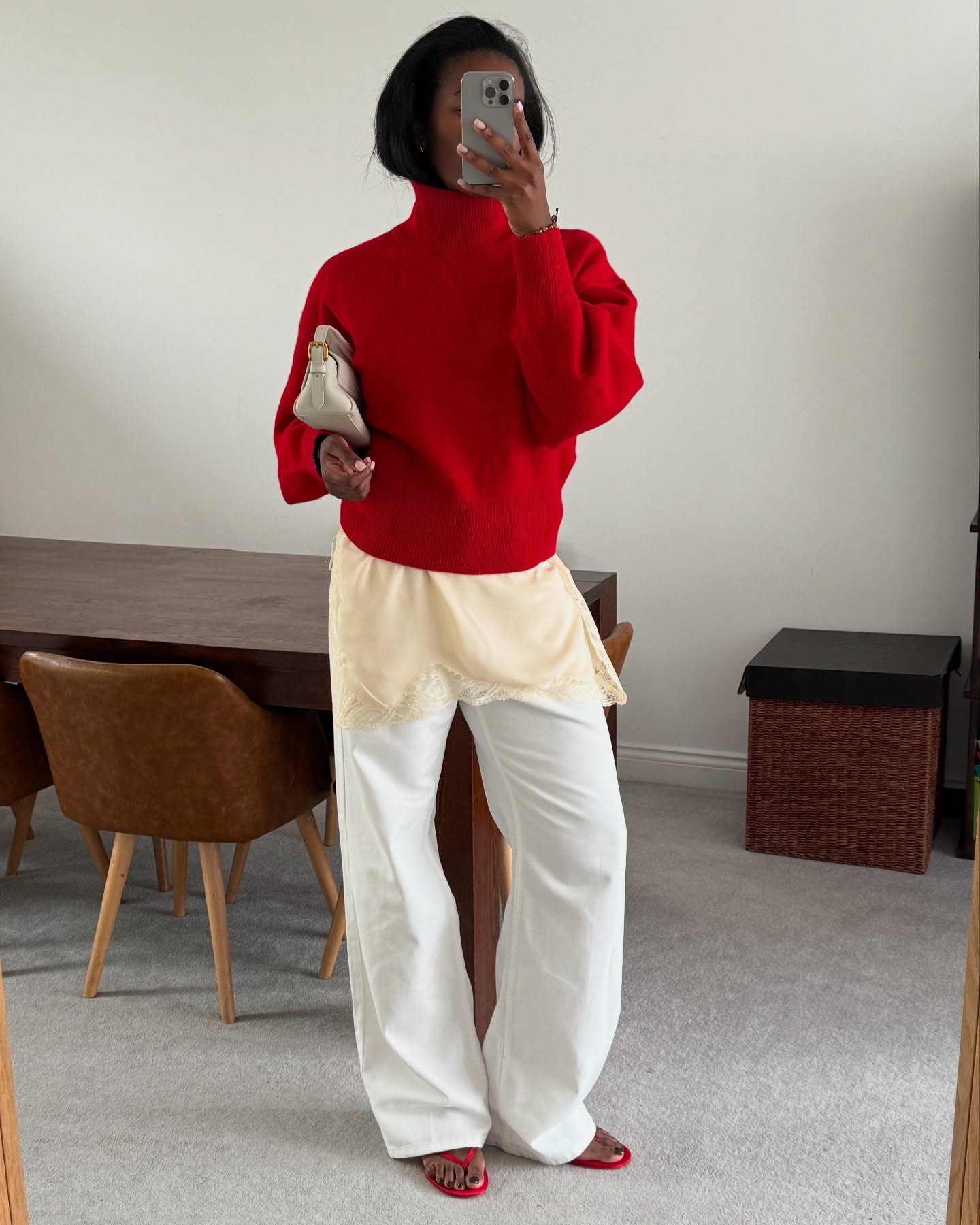 @nlmarilyn wearing a red turtleneck sweater over a slip dress with white jeans.