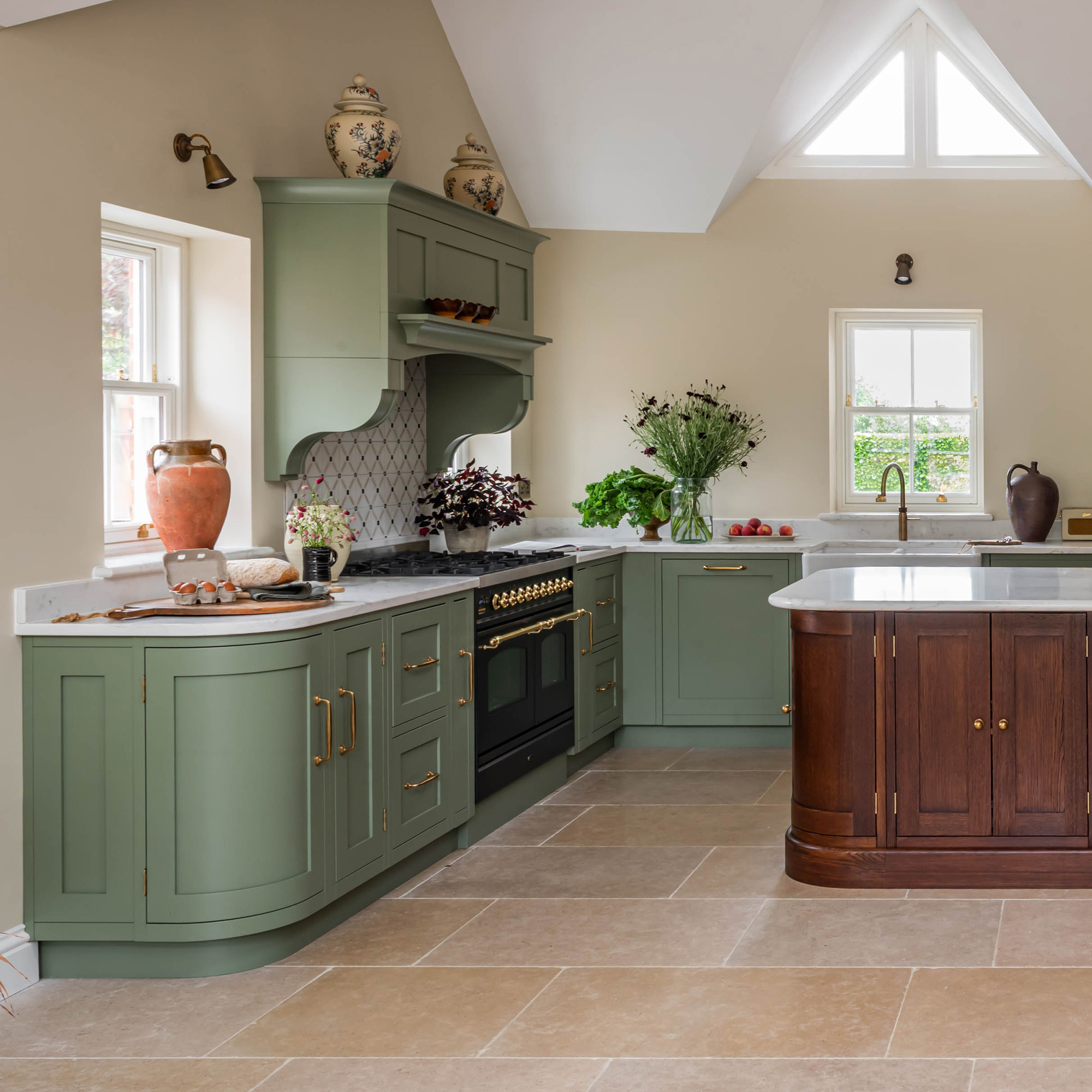 kitchen with cream wall green cabinetry and wooden curved kitchen island with stone floor